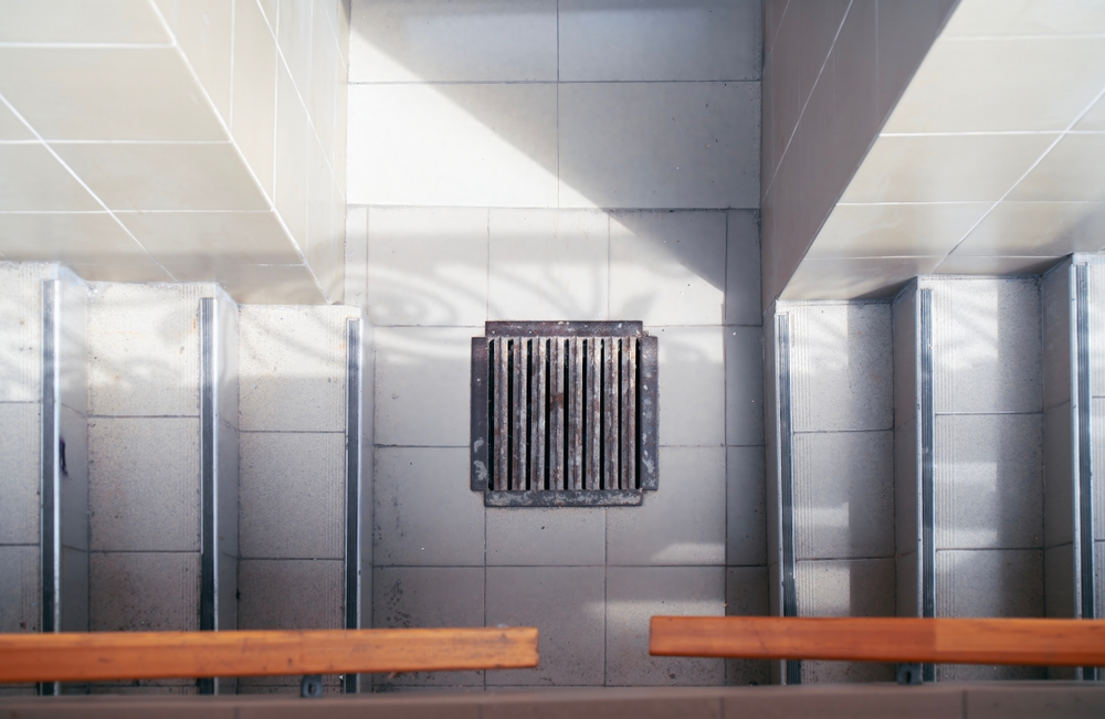 Metal,storm,drain,grate,positioned,between,two,concrete,staircases,leading
