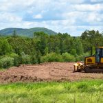 Yelllow,bulldozer,clearing,land,in,the,countryside,in,summer