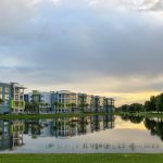 Large,retention,pond,reflecting,sky,,trees,,and,apartment,buildings,on