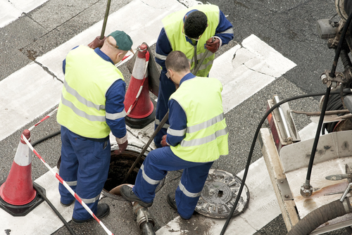 Utility,service,company,workers,moves,the,manhole,cover,to,cleaning